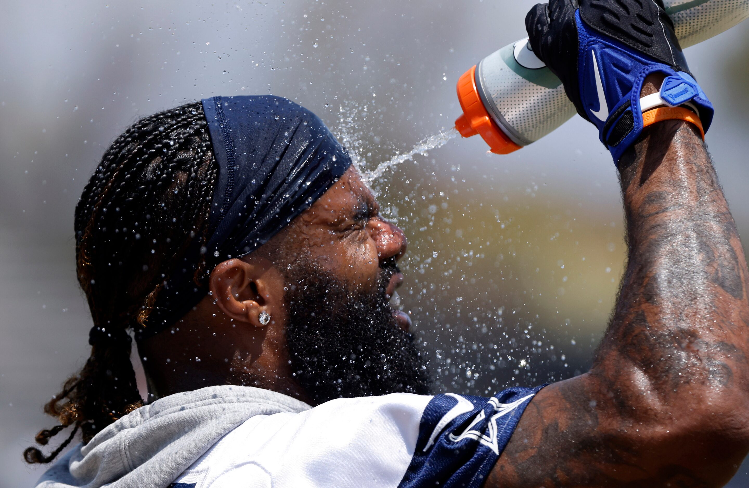 Dallas Cowboys running back Ezekiel Elliott (21) cools down with a bottle of water during...