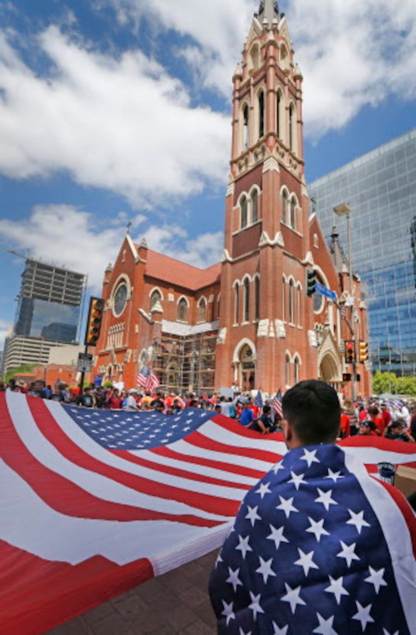 Christopher Rodríguez, de Oak Cliff ayuda a cargar una enorme bandera estadounidense. LOUIS...