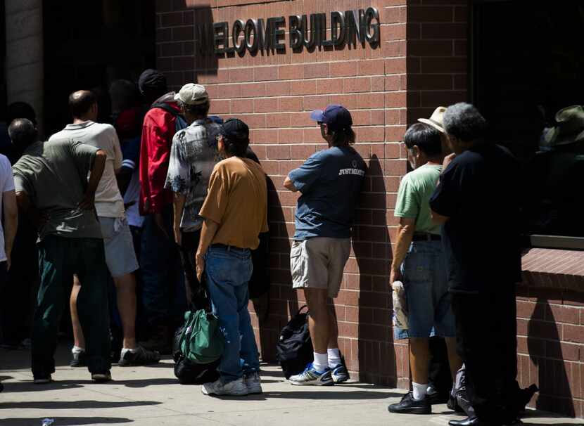 People wait in line at the welcome building inside The Bridge Homeless Recovery Center on...