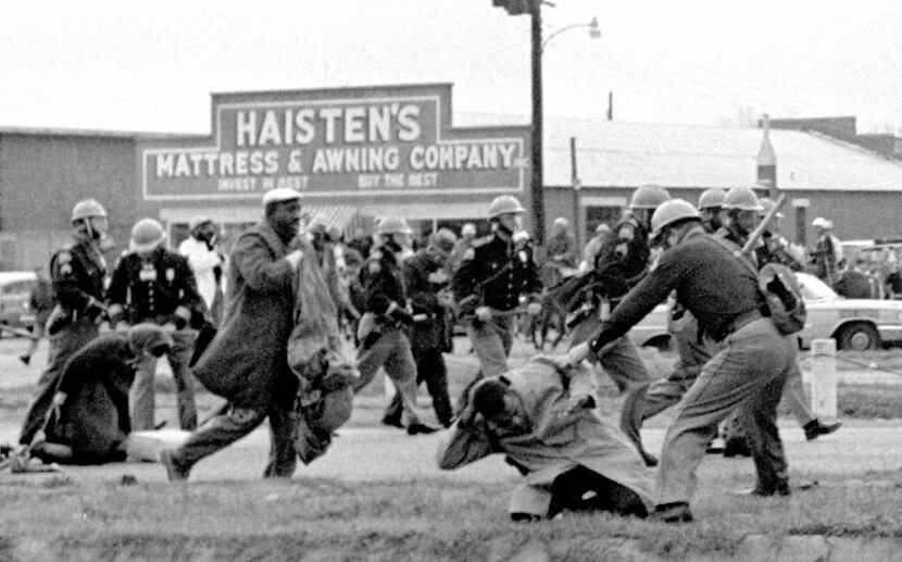 Alabama state troopers swing nightsticks to break up a civil rights voting march in Selma,...