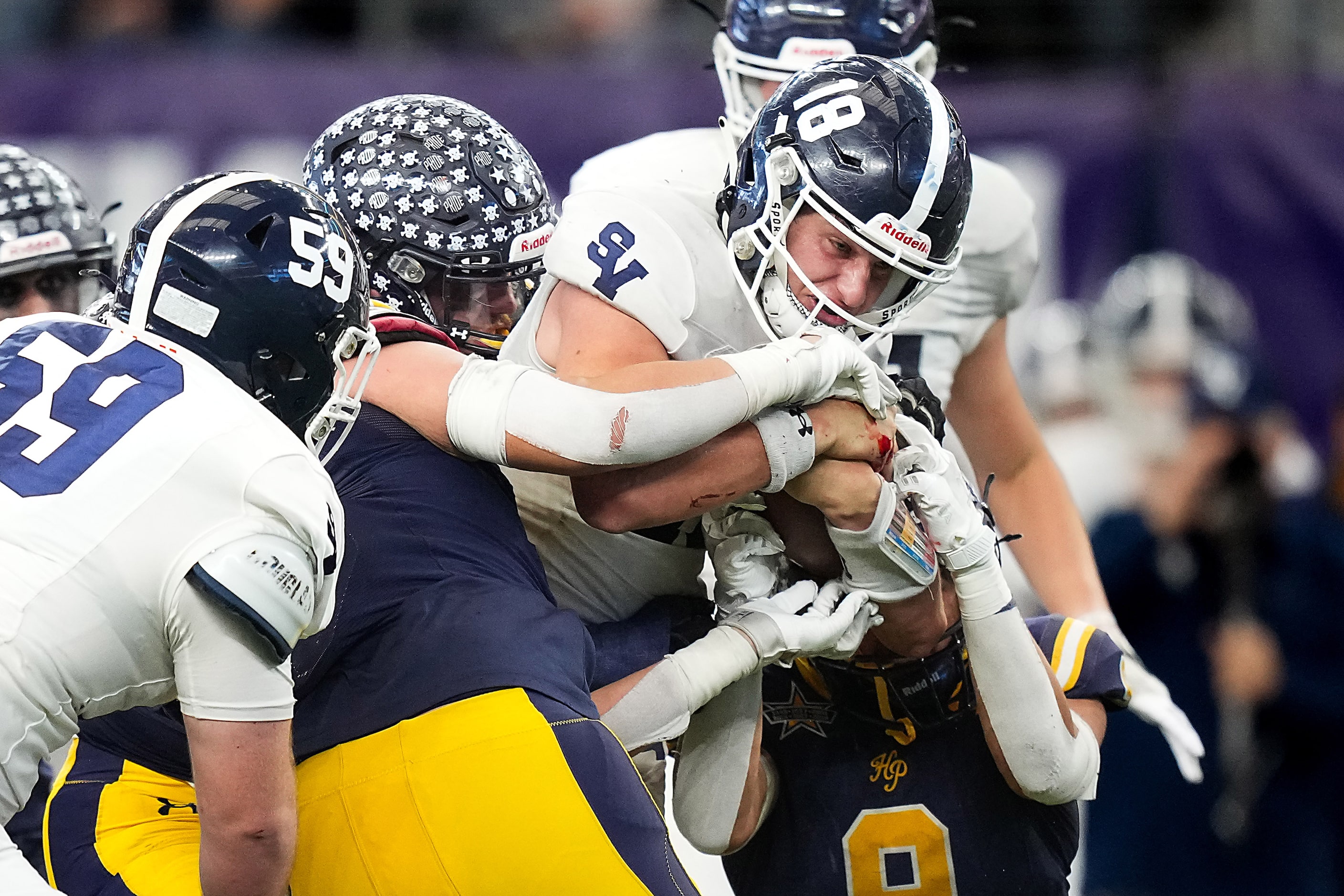 Smithson Valley's Cade Spradling (18) holds onto the ball as he is brought down by the...