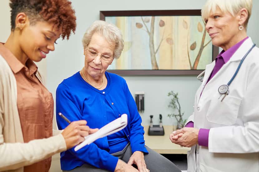 Doctor and patient advocate confer with elderly patient in a doctor's office.