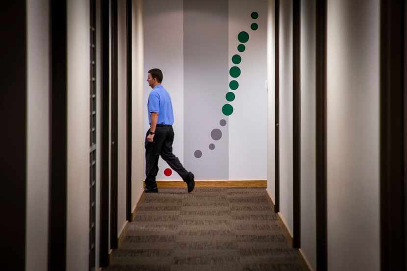 Alan Curry, a senior project manager, passes the "Dot Plot" painted on the walls showing...