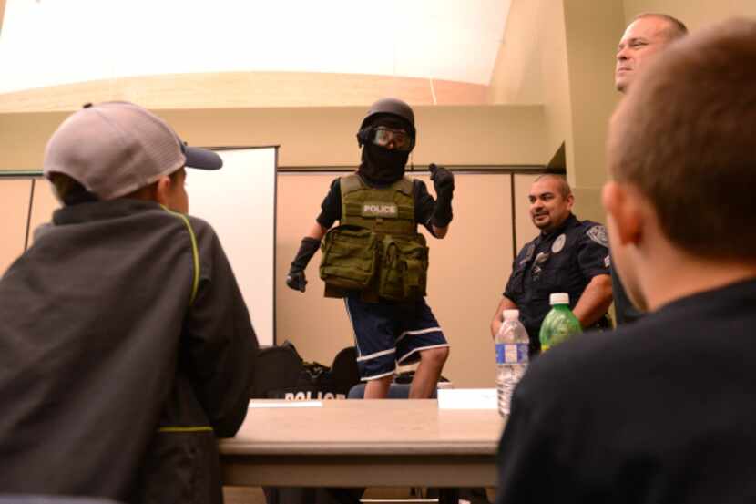 Ryan Lynch, 11, tries on Rowlett S.W.A.T. gear during the first youth police academy. The...