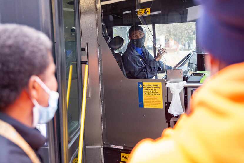 DART bus driver Michael Gasaway (center) helps Rodrick Grant (right) and Terry Johnson as...