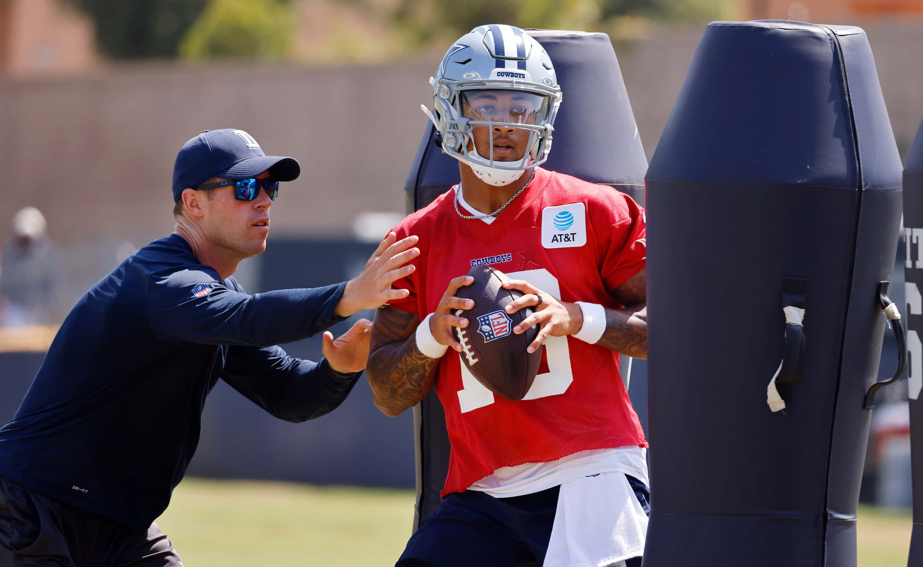 Dallas Cowboys quarterback Trey Lance (19) dodges the blocking dummies and the pass rush by...