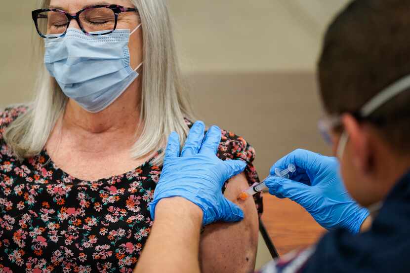 Cheryl McKay receives a COVID-19 vaccine from Arlington firefighter Derek O’Neill as part of...