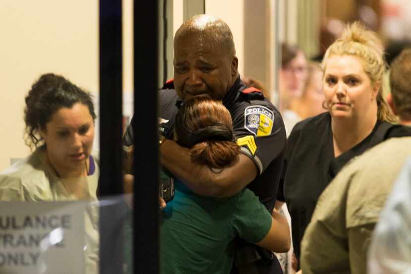 A DART police officer hugs another officer at Baylor University Hospital's emergency room...