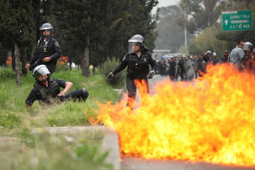 A riot police officer falls after protesters threw molotov cocktails at them near the...