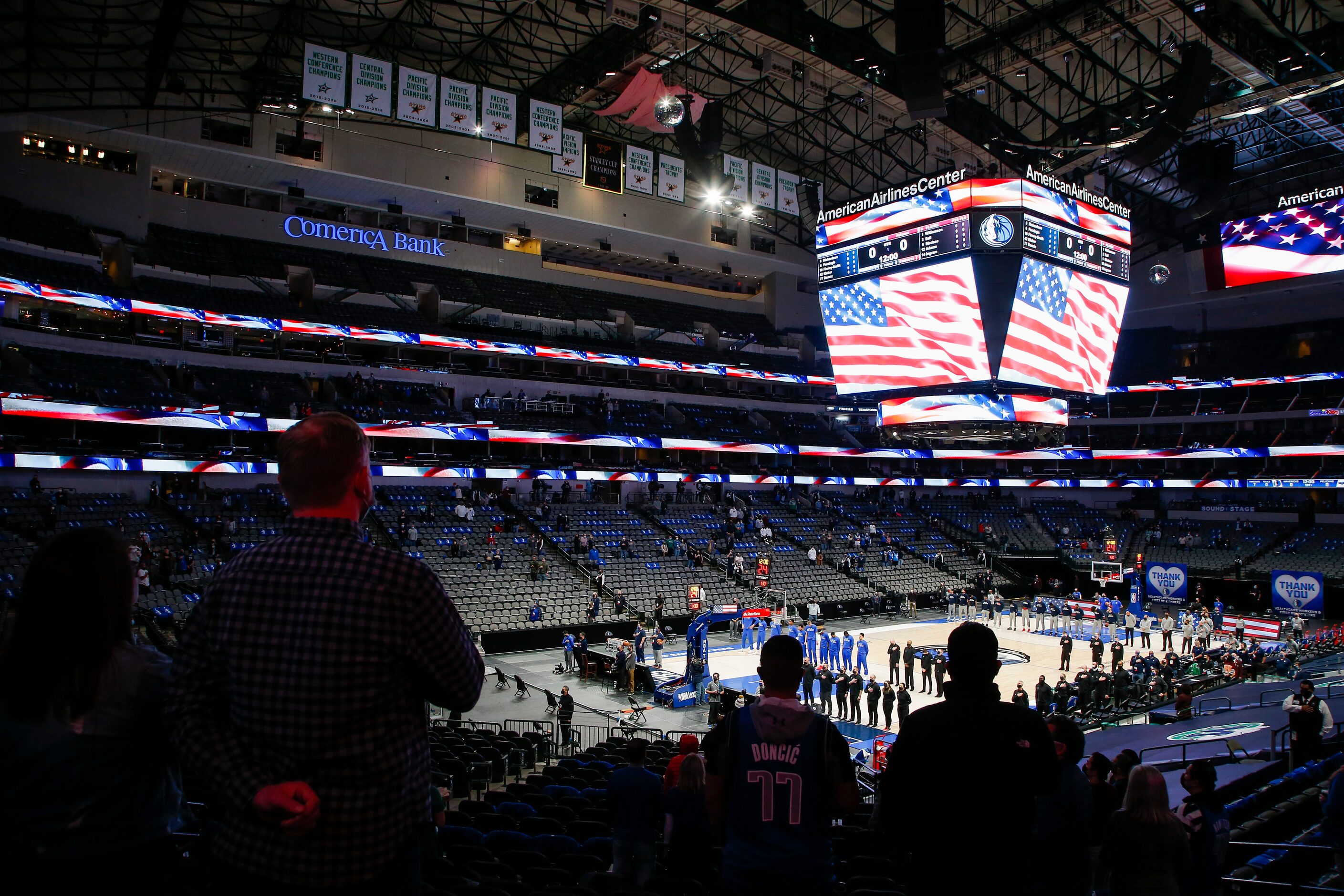 Fans, consisting mostly of healthcare workers, stand for the playing of the National Anthem...