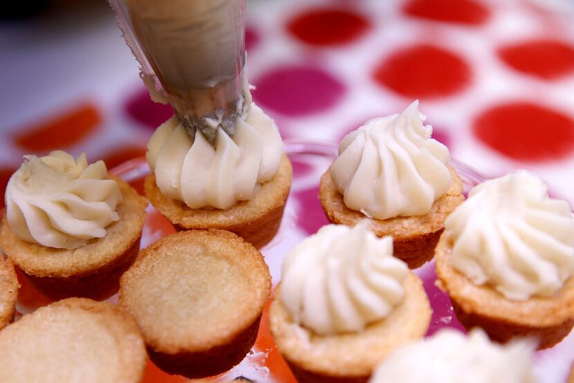 Pipe buttercream icing onto cookies.