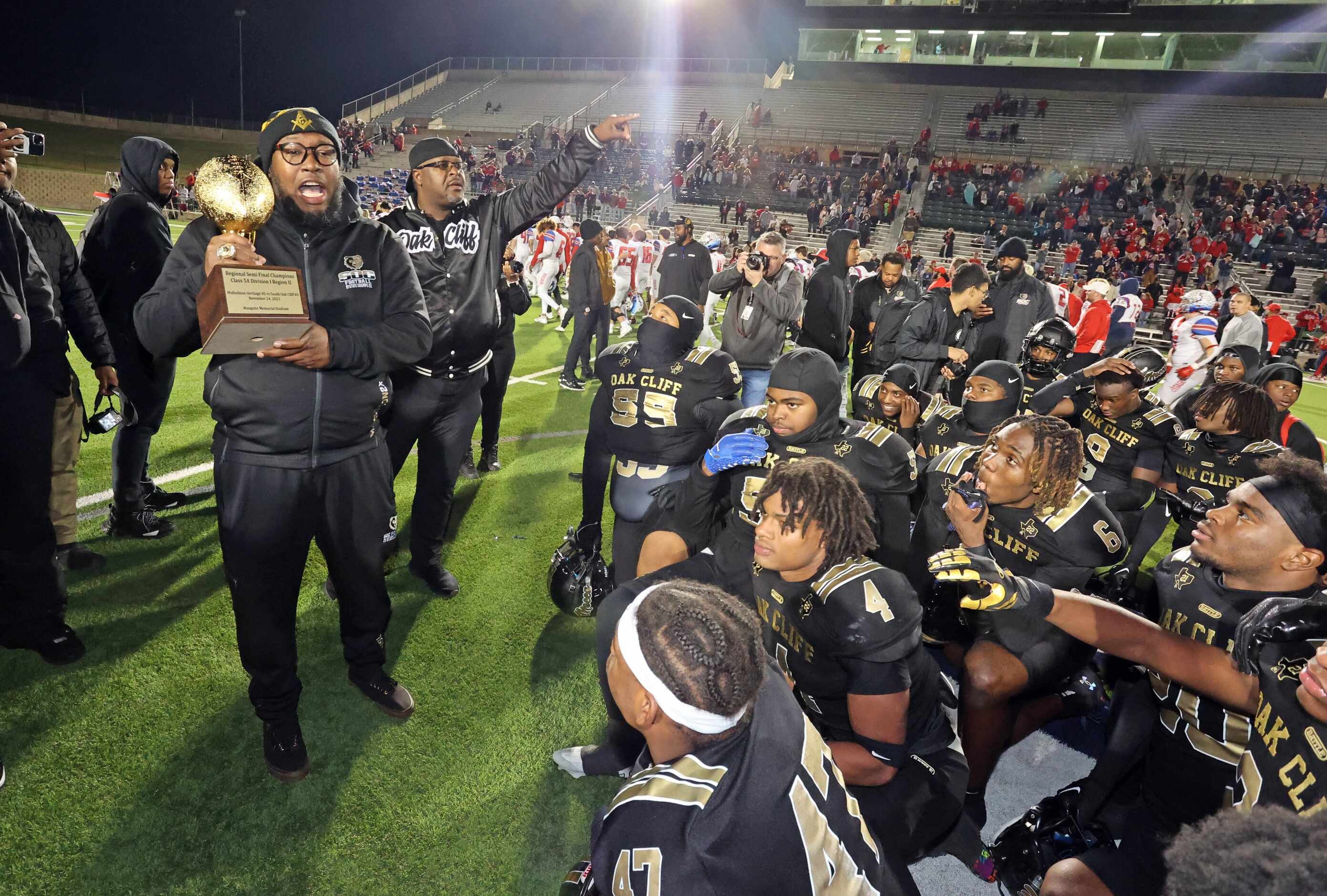 South Oak Cliff coaches show the Regional Semi-Finals trophy to the team, as they call a...