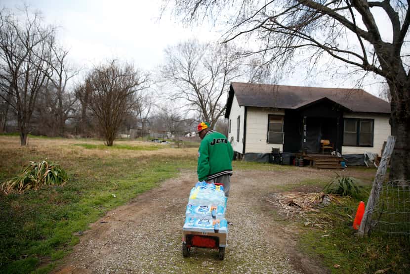 Demetrius X. Blair delivers cases of water from Mount Zion Baptist Church to a home down the...
