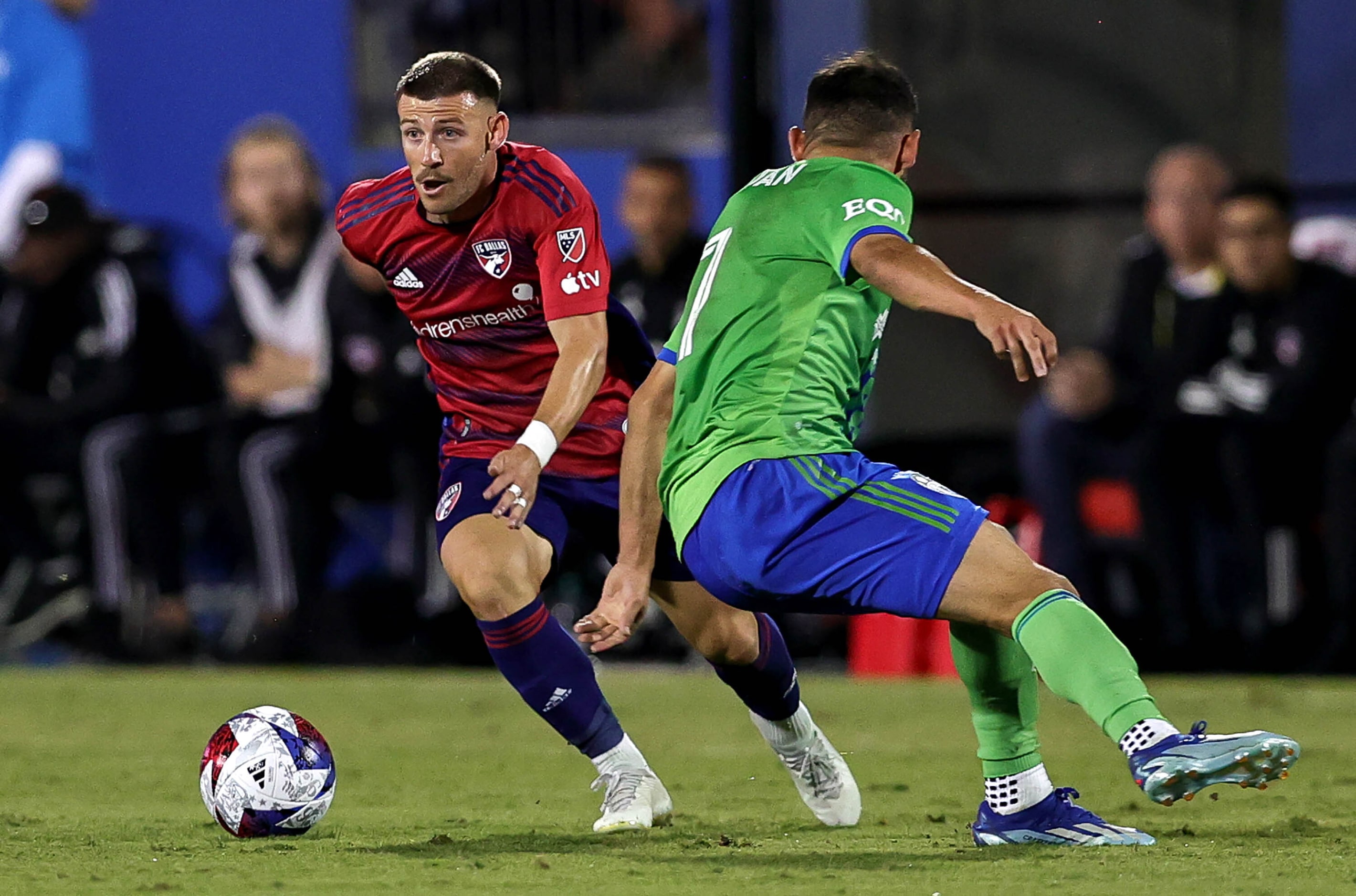 FC Dallas attacker Paul Arriola (7) looks to past Seattle midfielder Cristian Roldan (right)...