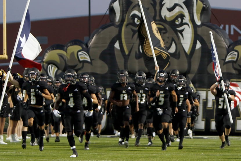 Members of the Royse City Bulldogs storm the field as they emerge from their team inflatable...