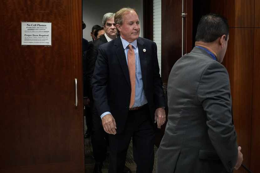 Texas Attorney General Ken Paxton (center) leaves the 185th District Court after a hearing...