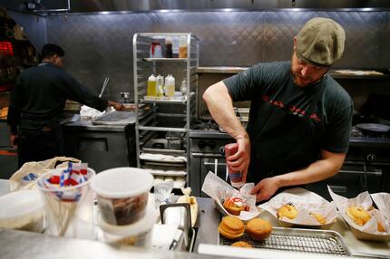 Pastry chef Justin Biggs works on making a "John Lennon" doughnut at Back Dough of Queenie's...