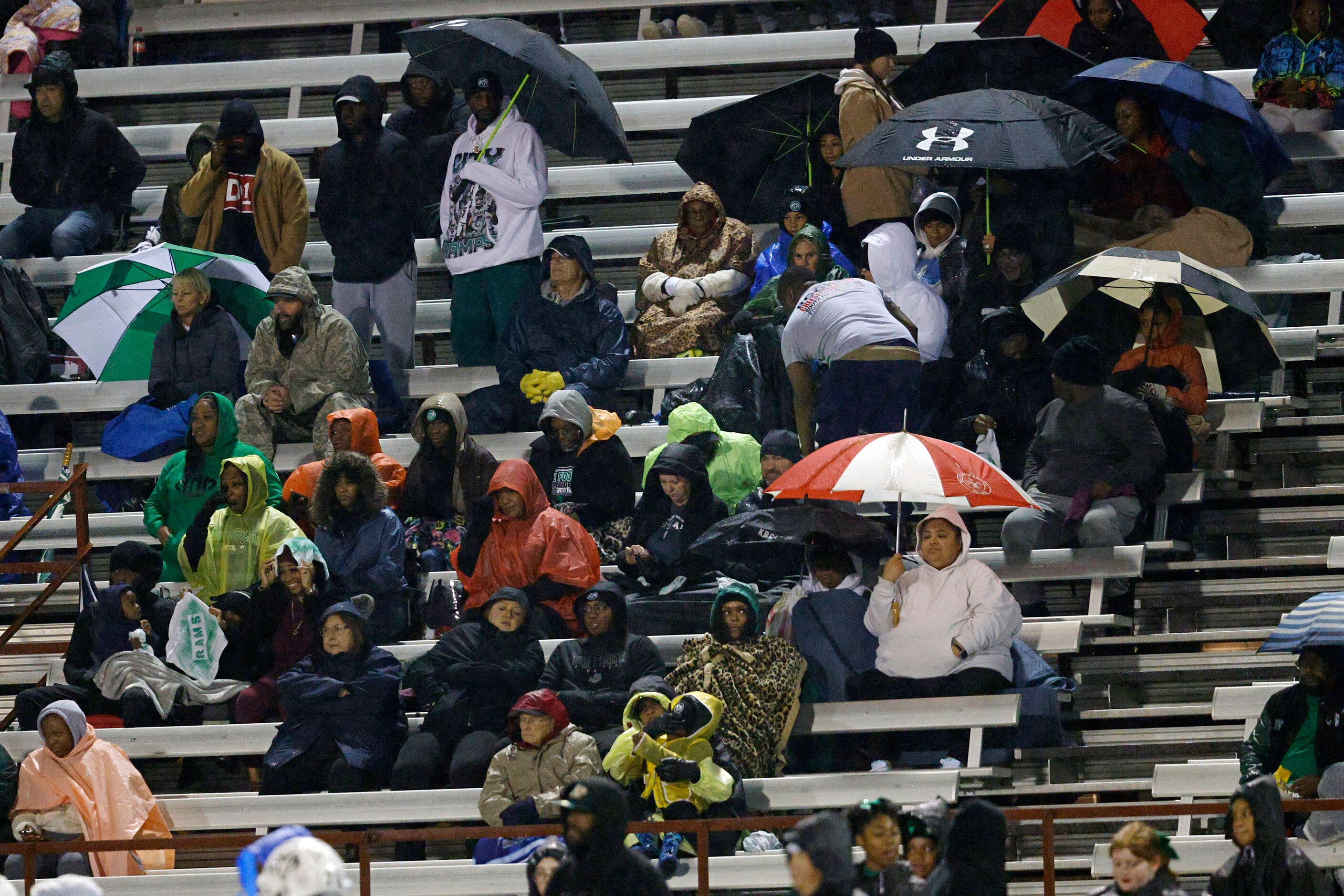 People sit on the stand in the rain during the first half of a high school Class 6A Division...