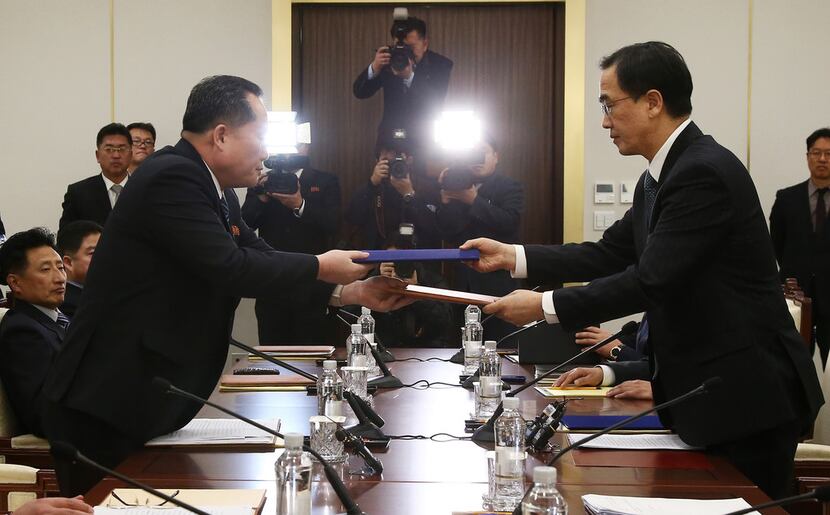 South Korean Unification Minister Cho Myoung-gyon, right, exchanges documents with the head...