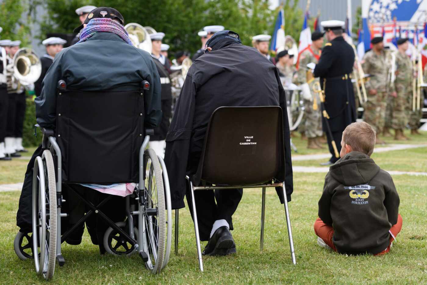 A young boy sits with World War II veterans during a ceremony to mark the 75th anniversary...