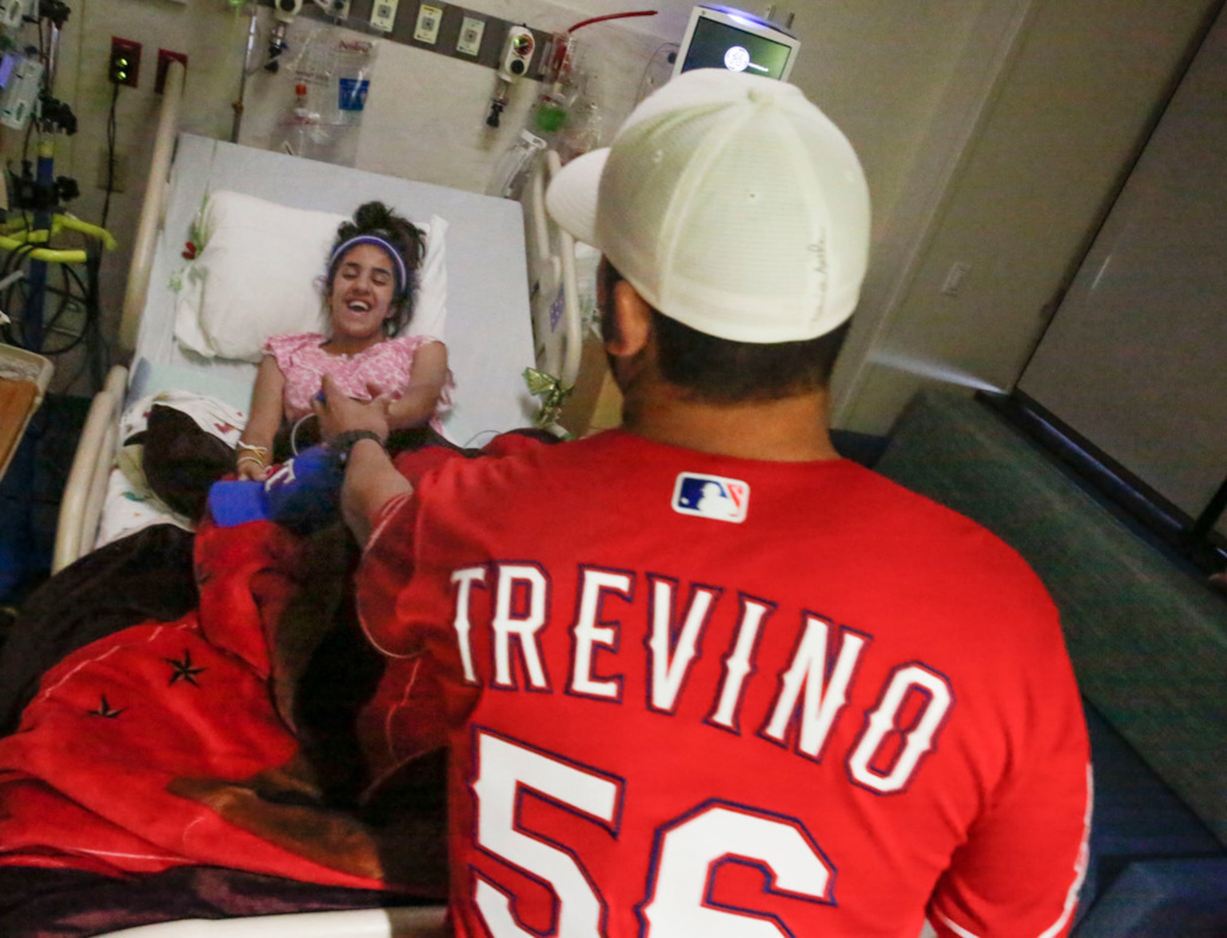 Texas Rangers catcher Jose Trevino hands a signed card to 15-year-old patient Azdahar "Star"...