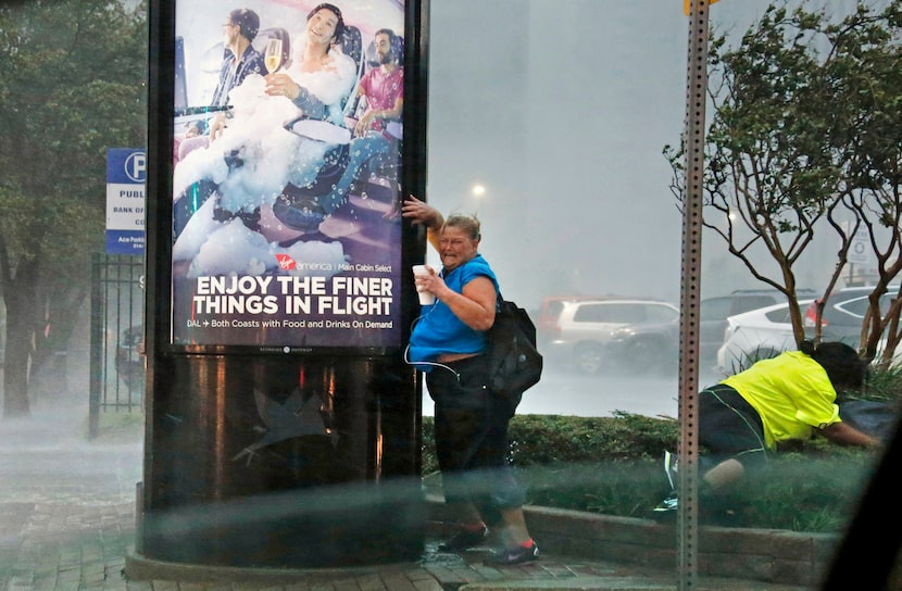 Pedestrians at Lamar and Elm streets in downtown Dallas fight against the wind as a storm...