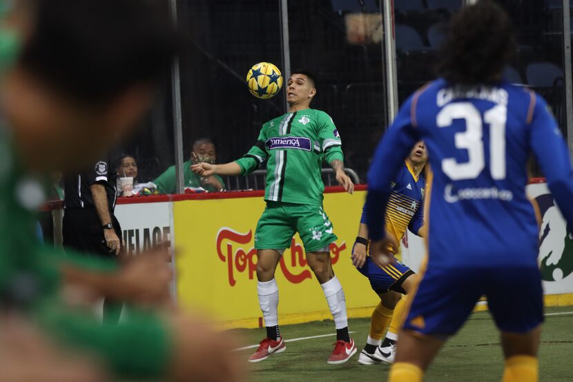 A Dallas Sidekicks player in a green uniform dodges a soccer ball at face level.