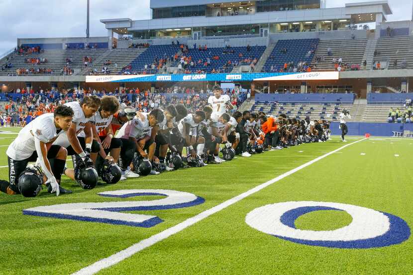 West Mesquite football players and coaches kneel at the 22 yard line in honor of former West...