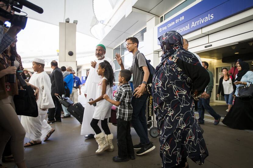 Ahmed Mohamed waves to assembled media as he departs the terminal with his family after...