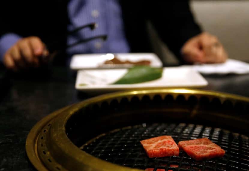 At a yakinku restaurant, such as Niwa Japanese BBQ in Deep Ellum (shown here), diners cook...
