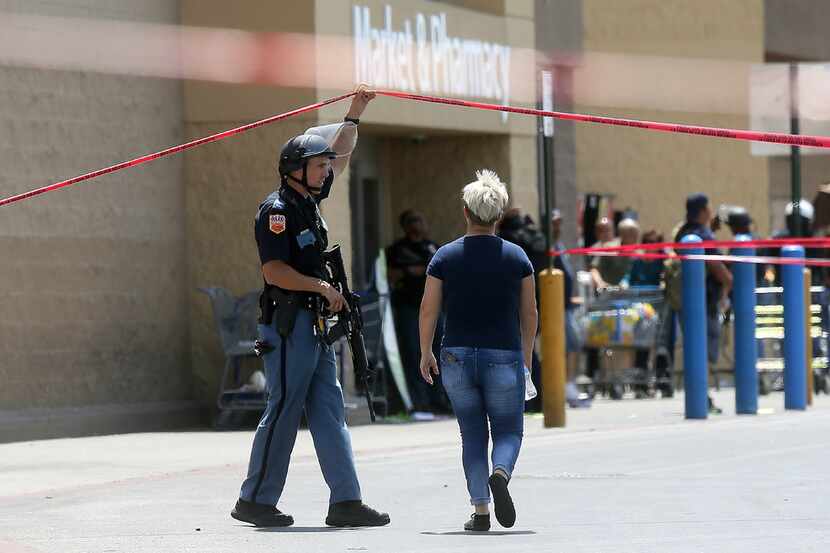 An employee crosses into the crime scene after Saturday's shooting at a Walmart in El Paso,