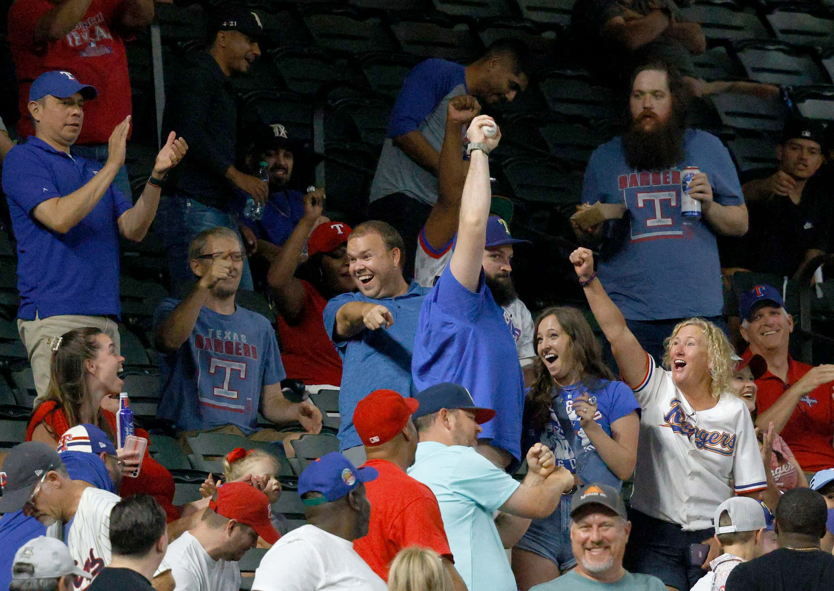 A fan gets a foul ball hit by Texas Rangers designated hitter Wyatt Langford (36) during the...