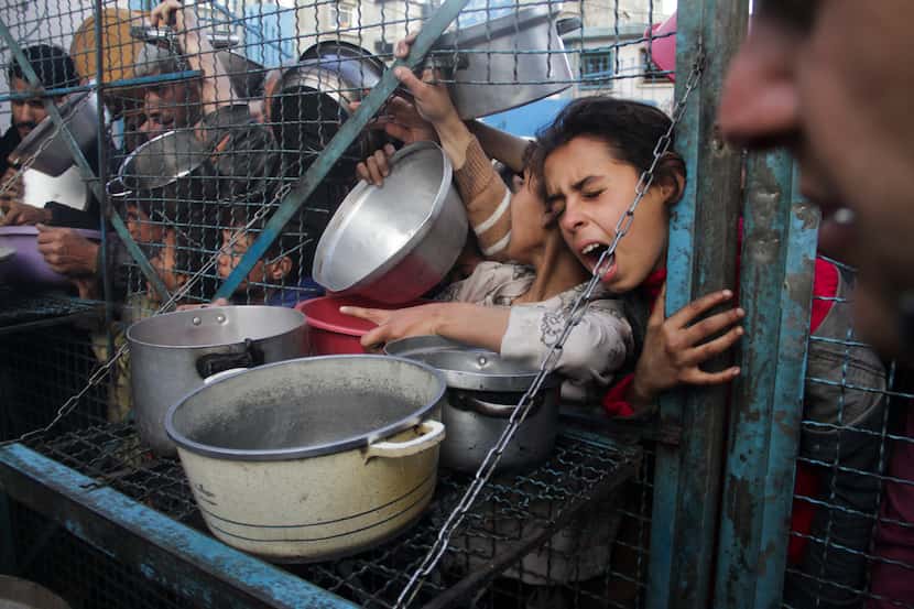 FILE - Palestinians line up to receive meals at Jabaliya refugee camp in the Gaza Strip,...