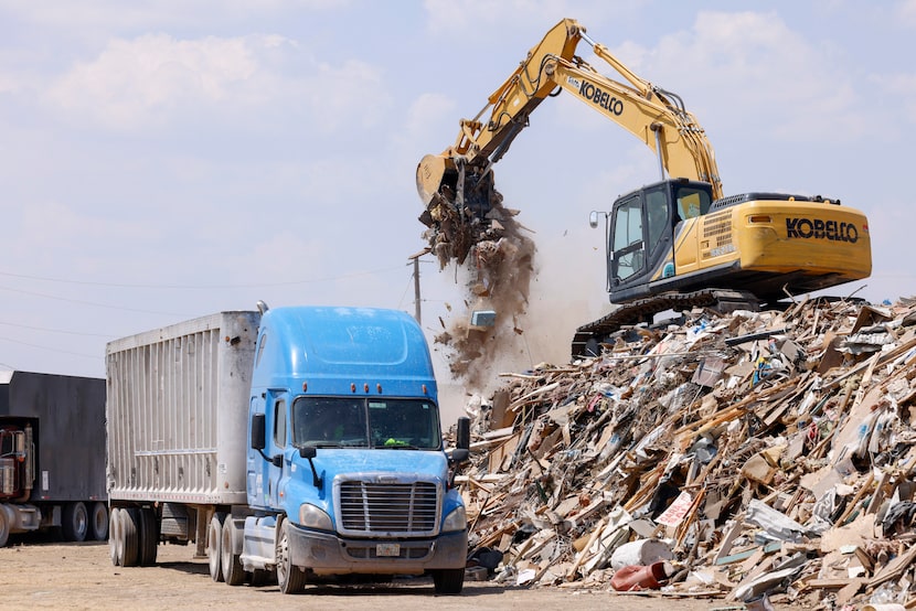 An excavator loads debris from a large collection site that was picked up in the area after...