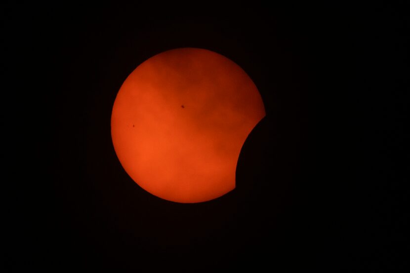 La primera fase del eclipse total de sol, visto entre nubes desde Arlington, Texas, el lunes...