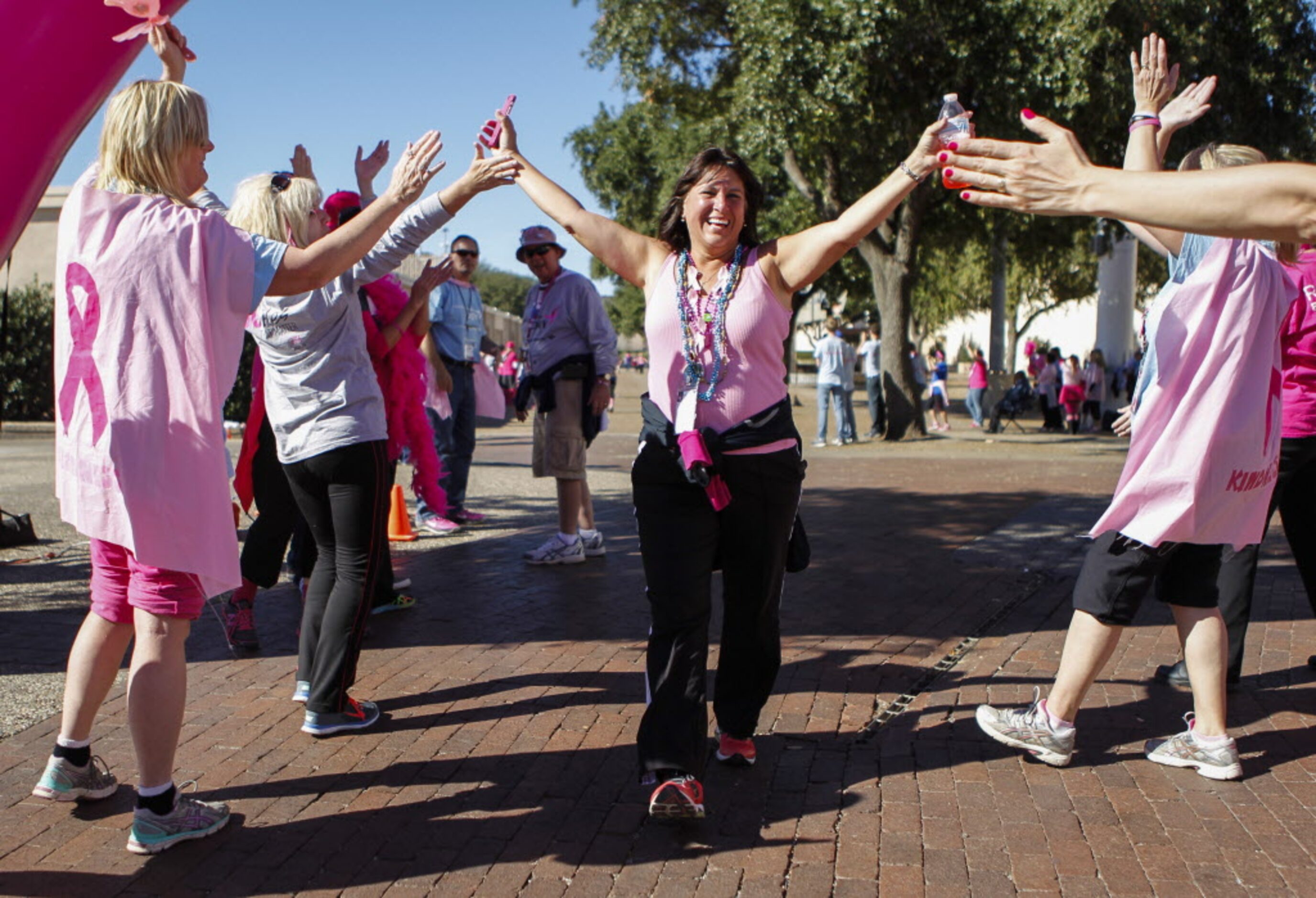 Volunteers greet and congratulate Debbie Conard of Richardson, Texas at the finish line of...