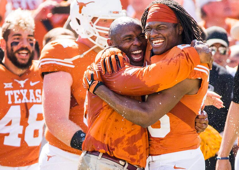 Texas head coach Charlie Strong hugs safety Adrian Colbert (26) after he is doused with a...