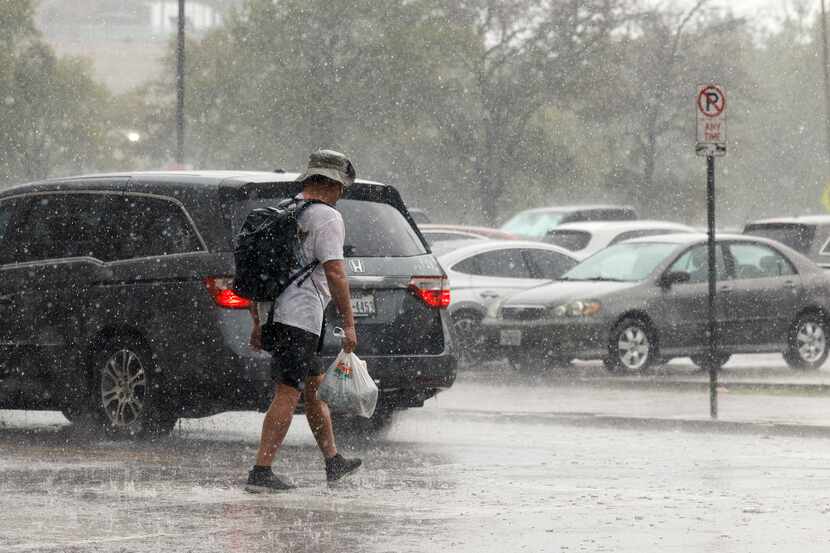A man walks across Lamar Street during a thunderstorm in downtown Dallas.