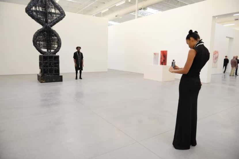 
Erika Oliver takes a photo of Charles Smith II next to “Elliptic Umbilic/Fait Accompli” by...