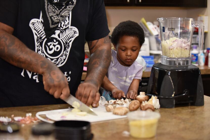 Captain McGee, 4, helps her father slice mushrooms as James McGee, left, prepares a vegan...