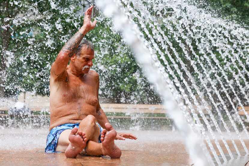 Richard Pokorny, living in Dallas for 46 years, relaxes by a water fountain as temperatures...