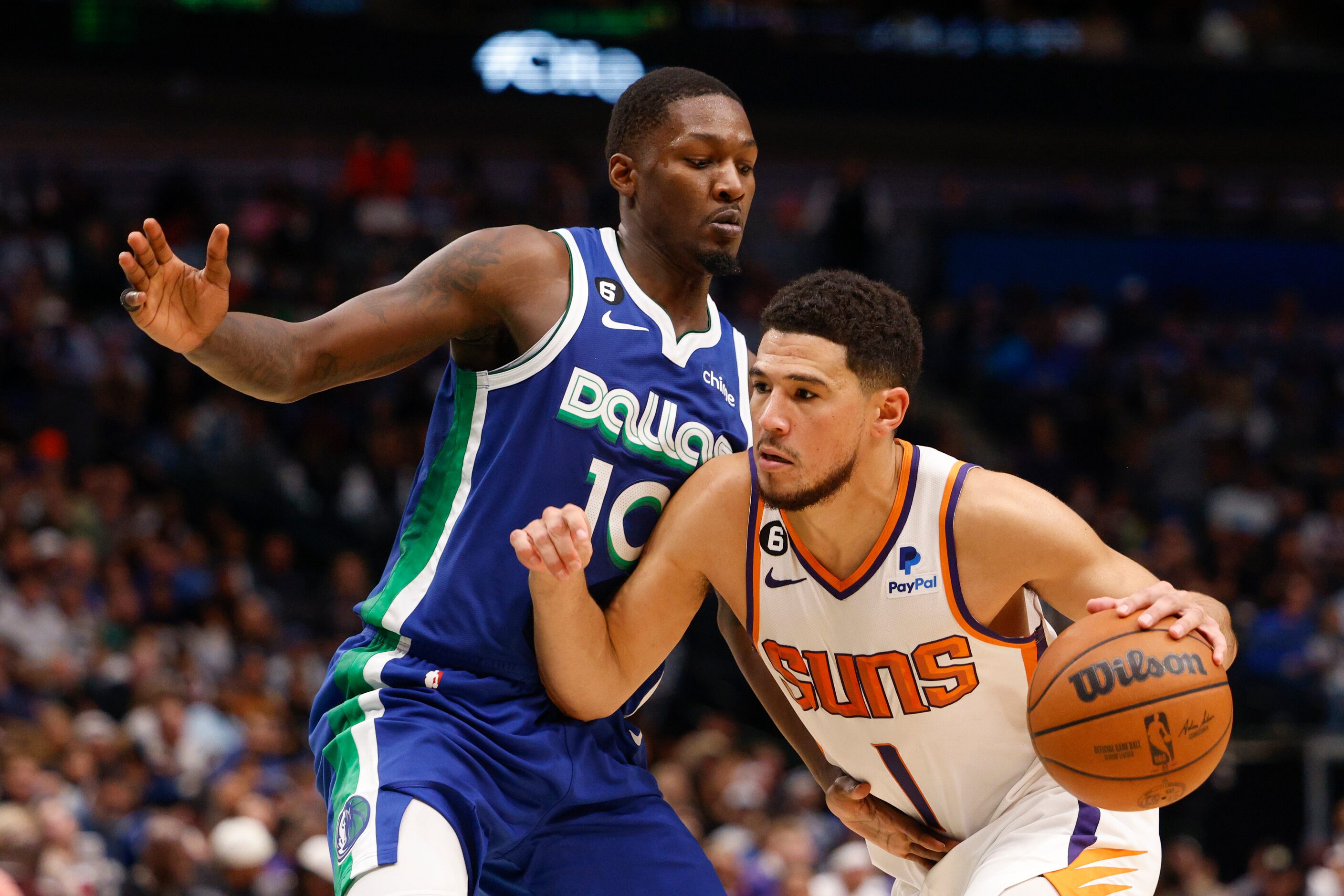 Phoenix Suns guard Devin Booker (1) dribbles against a defending Dallas Mavericks forward...