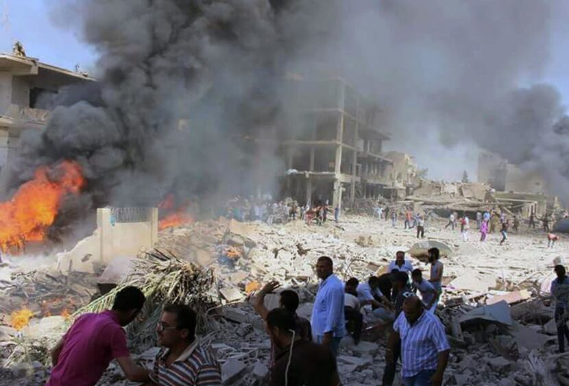 In this photo released by the Syrian official news agency SANA, Syrians gather at the scene...