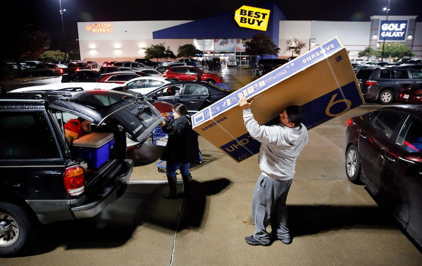 Thanksgiving Day shopper Jose Bazaldua of Dallas loads a 65-inch flat screen television into...