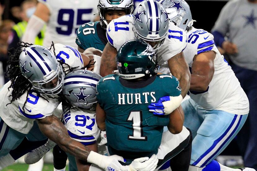 Eagles quarterback Jalen Hurts (1) is swarmed by Dallas Cowboys defenders, including middle...