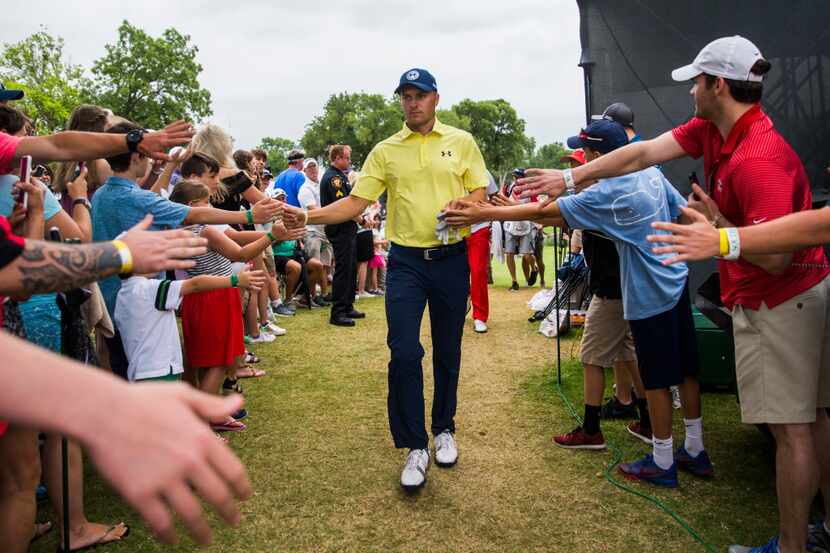 Jordan Spieth gets high-fives from fans as he walks from the 16th green to the 17th tee box...