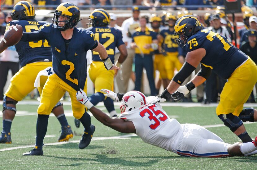 Southern Methodist Mustangs defensive end Delontae Scott (35) tries to hang on to Michigan...