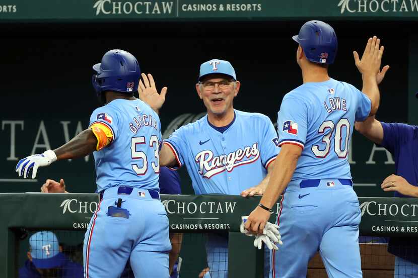 Texas Rangers' Adolis Garcia and Nathaniel Lowe (30) celebrate with manager Bruce Bochy,...