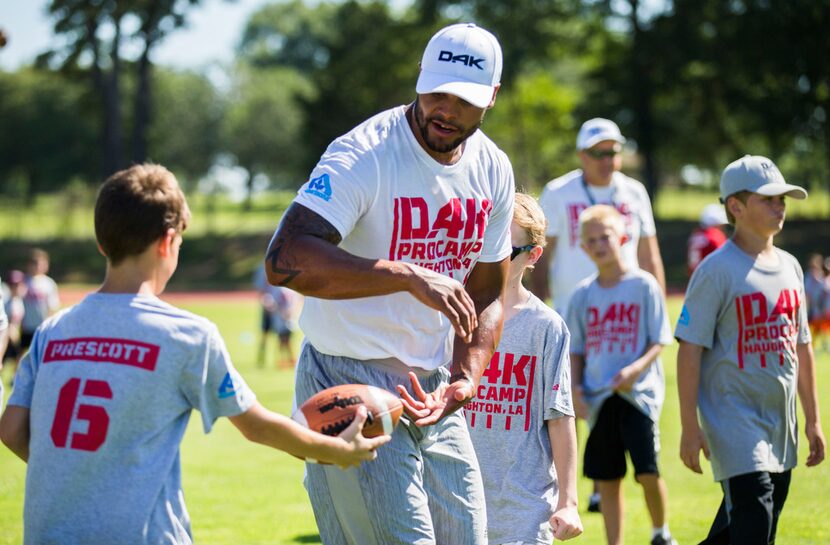 Dallas Cowboys quarterback Dak Prescott takes a handoff from a camper at his Dak Prescott...