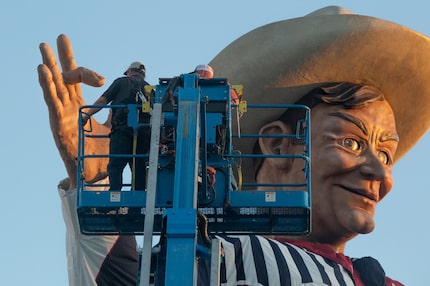 Fair Park personnel repair the drooping middle finger of Big Tex at Fair Park in Dallas on...